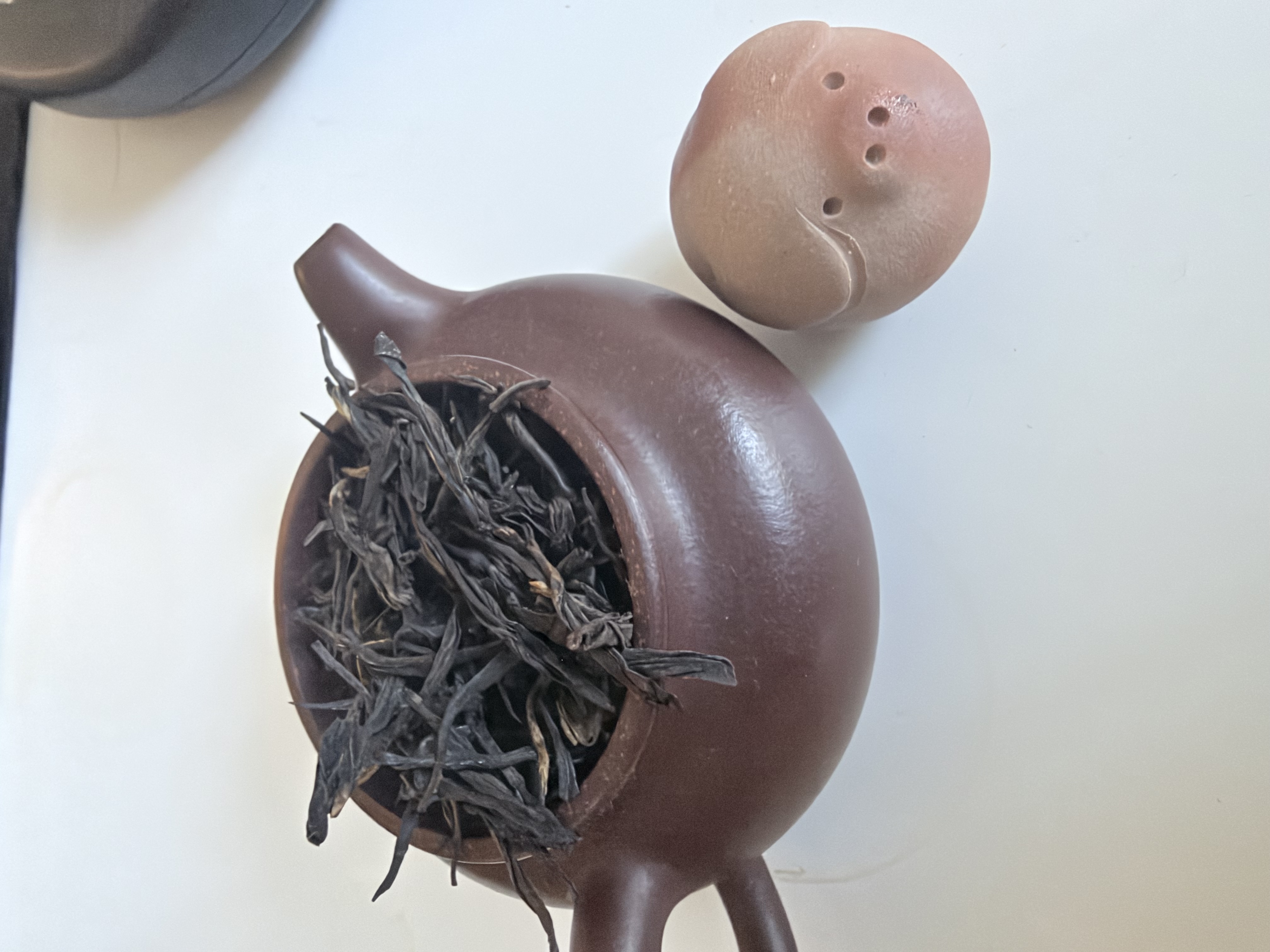 Dry Purple Needle black tea leaves in a clay teapot